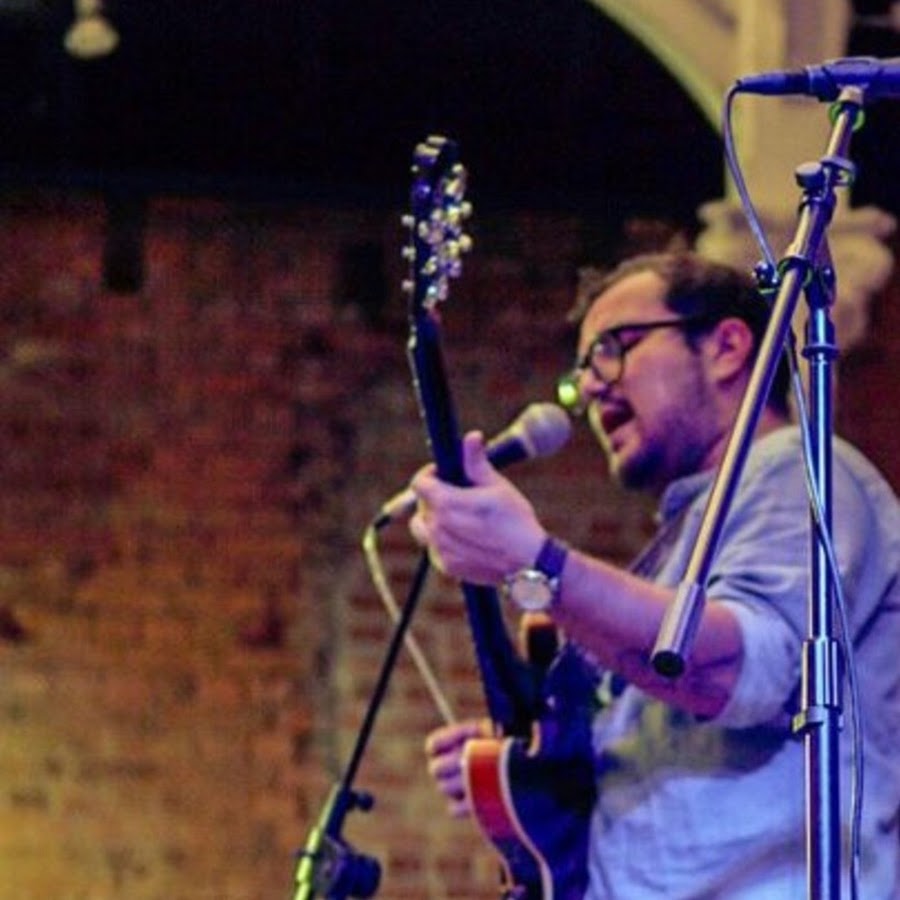 Guitarrista tocando en un escenario con luces moradas